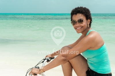 Mujer con gafas de sol en bicicleta en isla caribeña